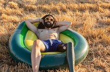 Smiling Shirtless Man With Prosthetic Leg Lying On Inflatable Ring Enjoying Sunny Day
