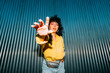 © VISTA by Westend61 - Young woman gesturing in front of corrugated wall