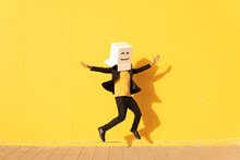 Carefree Man Wearing Box With Smiley Face Jumping In Front Of Yellow Wall On Footpath
