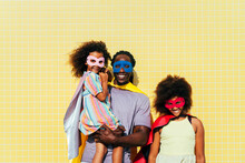 Smiling Father With Daughters Wearing Masks And Capes On Sunny Day