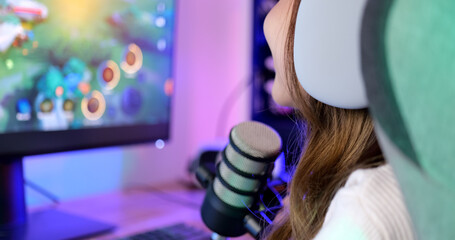 Close up view of young female gamer with long hair playing online game on computer at home, Gamer woman wearing headsets taking on microphone with teammates