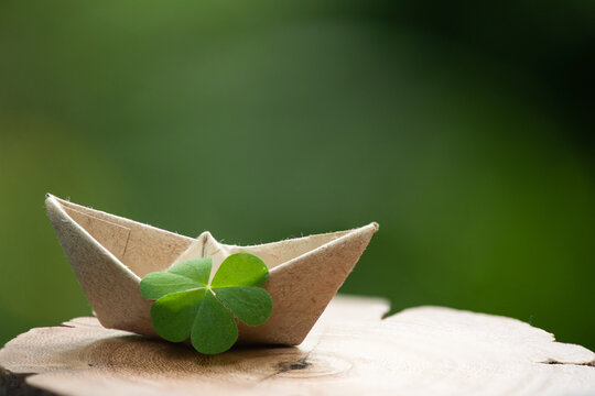 Clover leaf and paper boat on natute background.