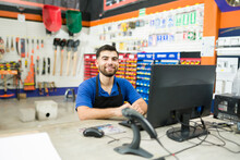 Happy hardware store employee at the computer desk at work