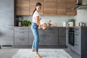 Little girl and happy mother with a cup of milk have a fun at home kitchen 