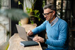 © Drobot Dean - Adult smiling man in glasses and headphones working with laptop