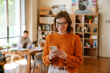 White ginger woman using cellphone while working at office