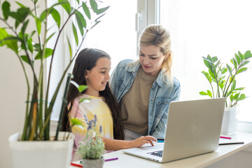 Wall Mural - Friendship of mom and her cute little daughter. They wallow at home in casual clothes and shopping online together using a laptop. They buy new toys for pretty little girl