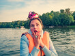 Middle aged woman with fancy hair wearing nautical lifejacket scared and amazed with open mouth for surprise, shocked face. Frightened girl at the lake