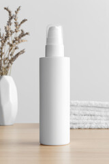 Poster - White cosmetic lotion bottle mockup with a lavender and towels on the wooden table.