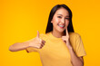 Happy woman take care tooth Give thumb up Young lady has nice smile fresh breath Beautiful asian girl has beautiful tooth, white teeth nice tooth alignment Pretty female show tooth Yellow background