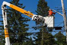 Hydro Worker On Bucket Lift At Hydro Pole Fixing A New Residential Electric Utlility Power Line