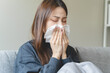 © Pormezz - Sick at home concept. Woman sneezing on the sofa in winter season.