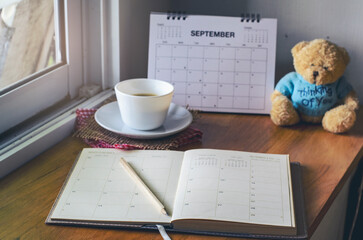 Wall Mural - agenda, planner book, teddy bear, and cup of coffee placed on office desk. diary for organizer to pl