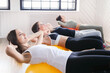Young fit women doing Pilates exercises with gym ball in fitness hall