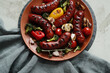 Picture of tasty hot grilled food with sausage and various vegeables on a red bowl