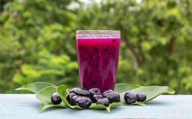 Jamun or Black Plum Juice in a Glass with Fruit and Leaves Isolated on Wooden  Background with Copy Space, Also Known as Malabar Plum, Syzygium Cumini or Jambolan