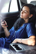 © racool_studio - Photo of a young, brunette woman in a blue dress holding mobile phone and sitting in her car