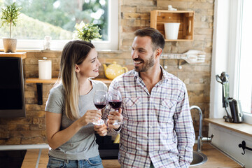 Wall Mural - Happy young couple enjoying while drinking wine at home