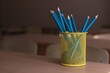 a yellow stand with pencils stands on a desk in a school classroom