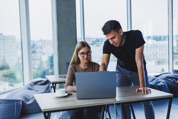 two colleagues are discussing work on a laptop. friendly relations in the office between colleagues.