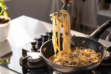 professional chef cook making vegetarian italian tagliatelle pasta with mushrooms and cream at moder