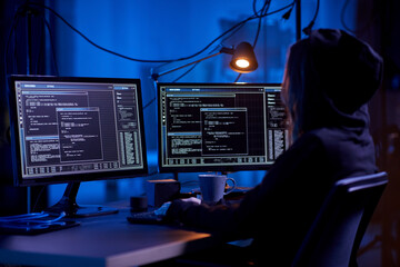 cybercrime, hacking and technology concept - female hacker in dark room writing code or using computer virus program for cyber attack