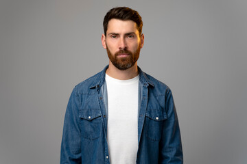 Attentive self confident bearded man looking at camera with serious expression