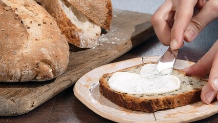 Closeup of hands spreading white sauce on bread