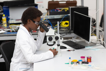  Scientist african american woman working in laboratory with electronic tech instruments and microscope. Research and development of electronic devices by color black woman.