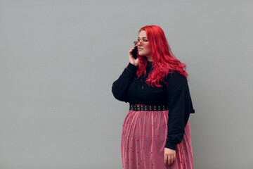 Wall Mural - European plus size woman speaking mobile phone. Young red pink haired body positive girl.