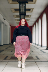 Wall Mural - European plus size woman walking outdoor street city. Young red pink haired body positive girl.