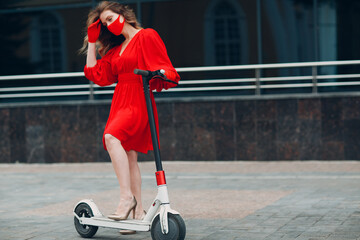 Wall Mural - Young woman with electric scooter in red dress and gloves with medical face mask at the city.