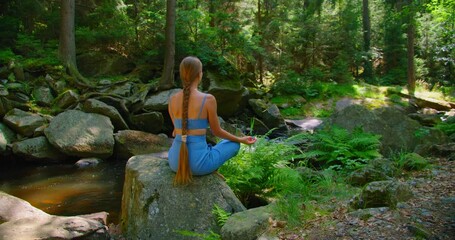 woman meditating, zen yoga meditation practice in nature. river stream in the forest. rear view of g