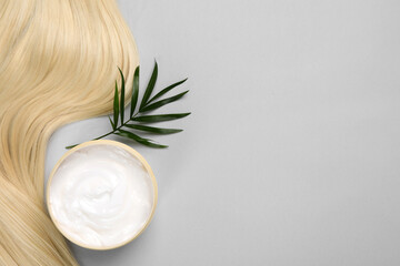 Wall Mural - Lock of healthy blond hair, cosmetic product and green twig on light grey background, flat lay. Space for text