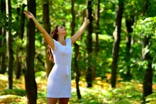 Jeune Femme Brune En Robe Blanche Qui Lève Les Bras Vers Le Ciel Dans Une Forêt, France, Europe, 1