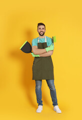 Wall Mural - Man with brush and dustpan on orange background