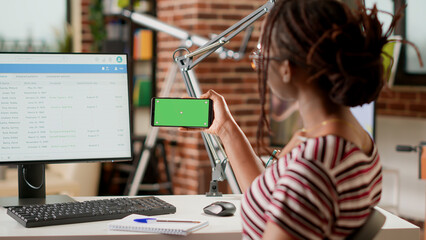 Poster - African american freelancer using horizontal greenscreen on mobile phone, looking at isolated mockup template with chroma key background and blank copyspace. Holding smartphone.