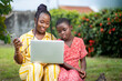 image of beautiful african lady and a kid with smart phone and laptop enjoying internet
