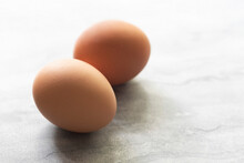 Two Whole Chicken Eggs On A Textured White Background.