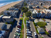 An Aerial Shot Of The Apartments And Houses In The Cityscape Along Rosie's Dog Beach With Parked Cars And Lush Green Palm Trees, Grass And Plants And Blue Sky In Long Beach California USA