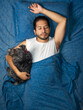 © Narayan - latin man sleeping in bed with his friend dog, sleep concept