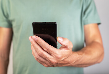 Aufkleber - Man holding phone for checking social media, surfing Internet, looking through photos and news articles. Male hands with smartphone closeup