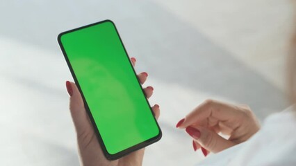 Woman holding a phone in hands with green screen