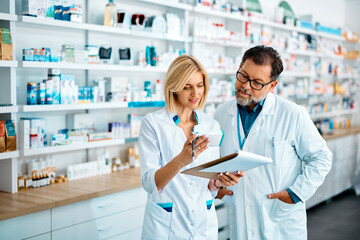 female pharmacist and her mature colleague checking inventory while working in drugstore.