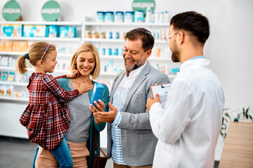 Wall Mural - Happy family choosing product with help of pharmacist in drugstore.