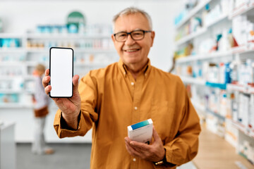 Wall Mural - Close up of senior man showing blank screen on smart phone while buying medicine in drugstore.