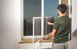 © andranik123 - Man installing the mosquito net on the window.