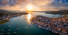 Aerial Panorama Of The City And Harbor Of Poros Island In The Saronic Gulf, Greece, During A Colorful Summer Sunset