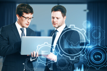 Aufkleber - Two attractive young european businessmen with laptop and glowing cogwheel and chart hologram on blurry office interior background. Business analytics, teamwork and finance concept. Double exposure.