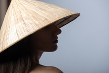 Fashion, Travel And Lifestyle Concept. Portrait Of Beautiful Woman With Naked Shoulder And Long Dark Hairs Wearing Traditional Cone-shaped Asian Cane Hat And Cover Her Face In Shade. Face Is In Focus